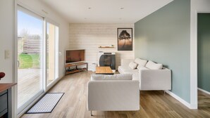 A modern living room with a sofa, a coffee table, a TV, and a fireplace. - House with pool for 8 - 500m from the beach (Plobannalec-Lesconil)