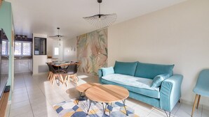 Ein modernes Wohnzimmer mit einem türkisfarbenen Sofa, einem Holztisch und einem Essbereich mit einem Holztisch und Stühlen.