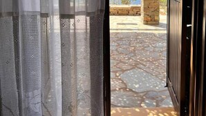 A doorway with a view of a stone patio and a stone pillar. - Holiday House - Koundouros Panoramic Sea View (Kea)