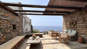 A stone patio with outdoor furniture, a view of the sea, and a pergola structure. - Holiday House - Koundouros Panoramic Sea View (Kea)