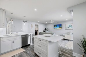A modern kitchen with white cabinetry, a built-in dishwasher, and a central island with a bowl.