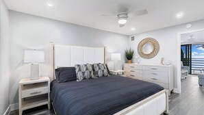 Un dormitorio moderno con cama, mesitas de noche, cómoda y ventilador de techo.