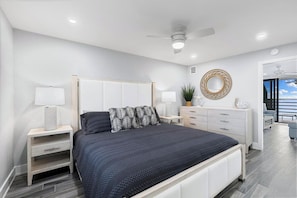 Un dormitorio moderno con cama, mesitas de noche, cómoda y ventilador de techo.