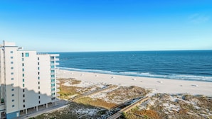 Een hotel aan de kust met uitzicht op het strand, een parkeerplaats en een voetpad naar het strand.