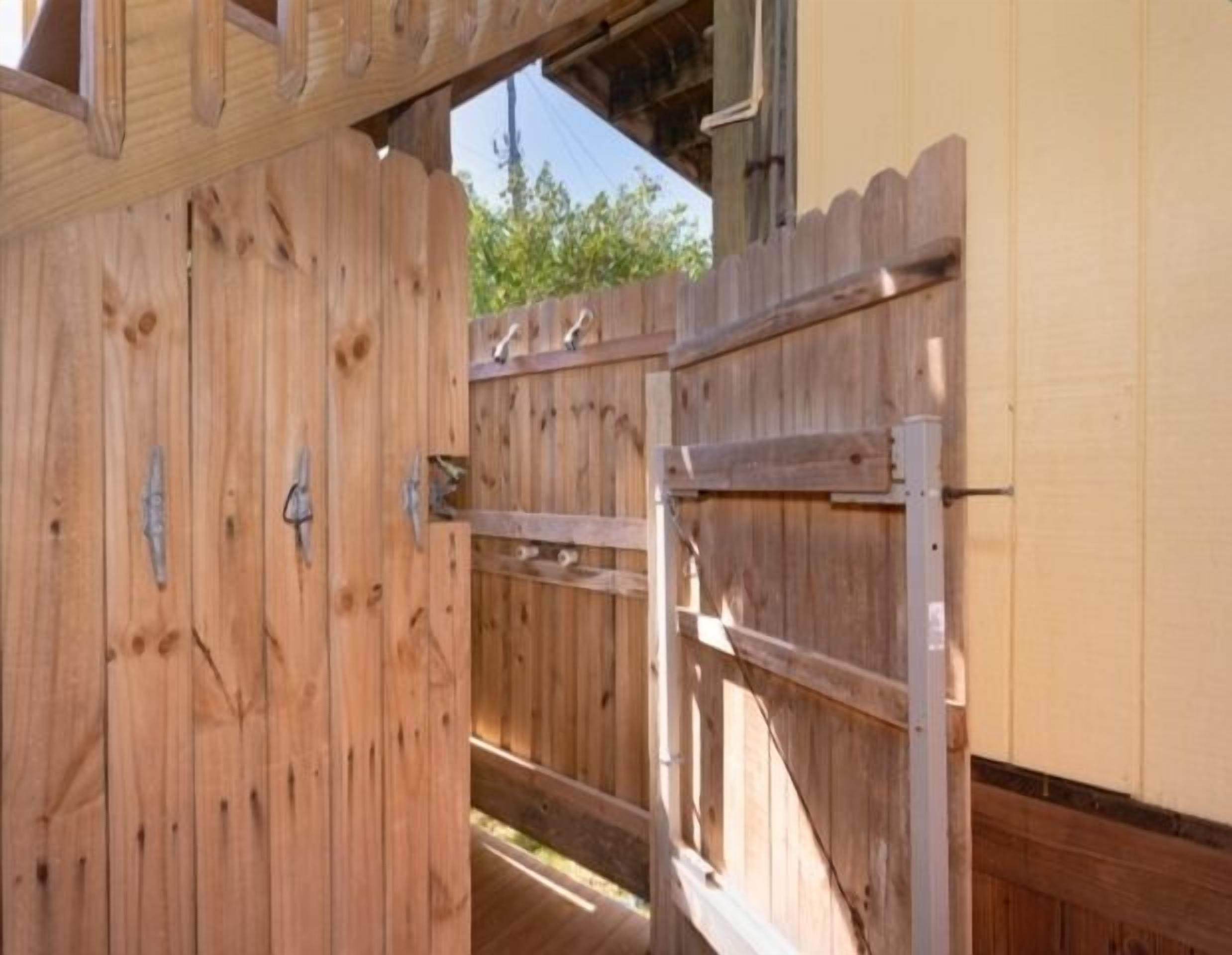 A wooden gate leading to a building with a beige exterior wall.