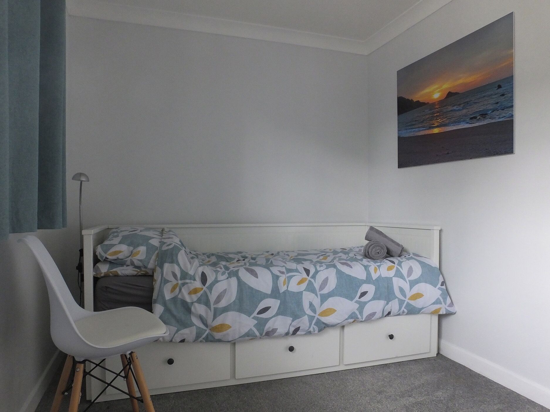 A bedroom with a bed, a chair, a painting, and a window.