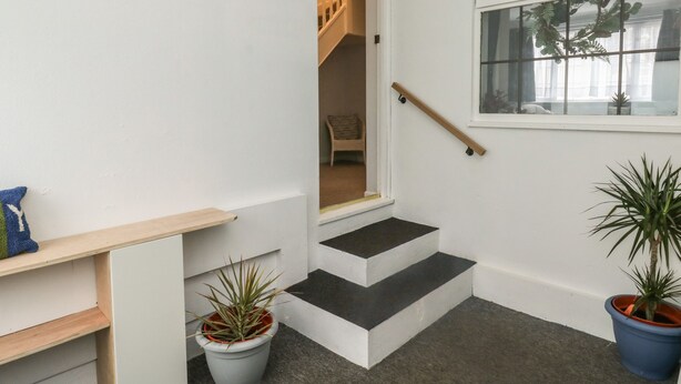 Un escalier avec une rampe, une petite plateforme et une fenêtre ornée de plantes.