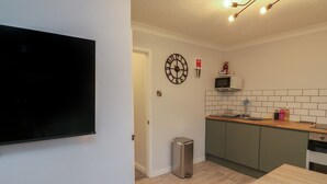 Une cuisine moderne équipée d’un four à micro-ondes, d’une horloge et d’une poubelle.