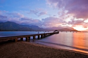 A pier extending into calm waters with mountains in the background.