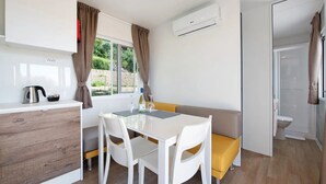 Uma cozinha compacta com área de refeições, forno embutido e janela com cortinas.