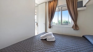 Quarto com cama, cortinas, janela e porta.