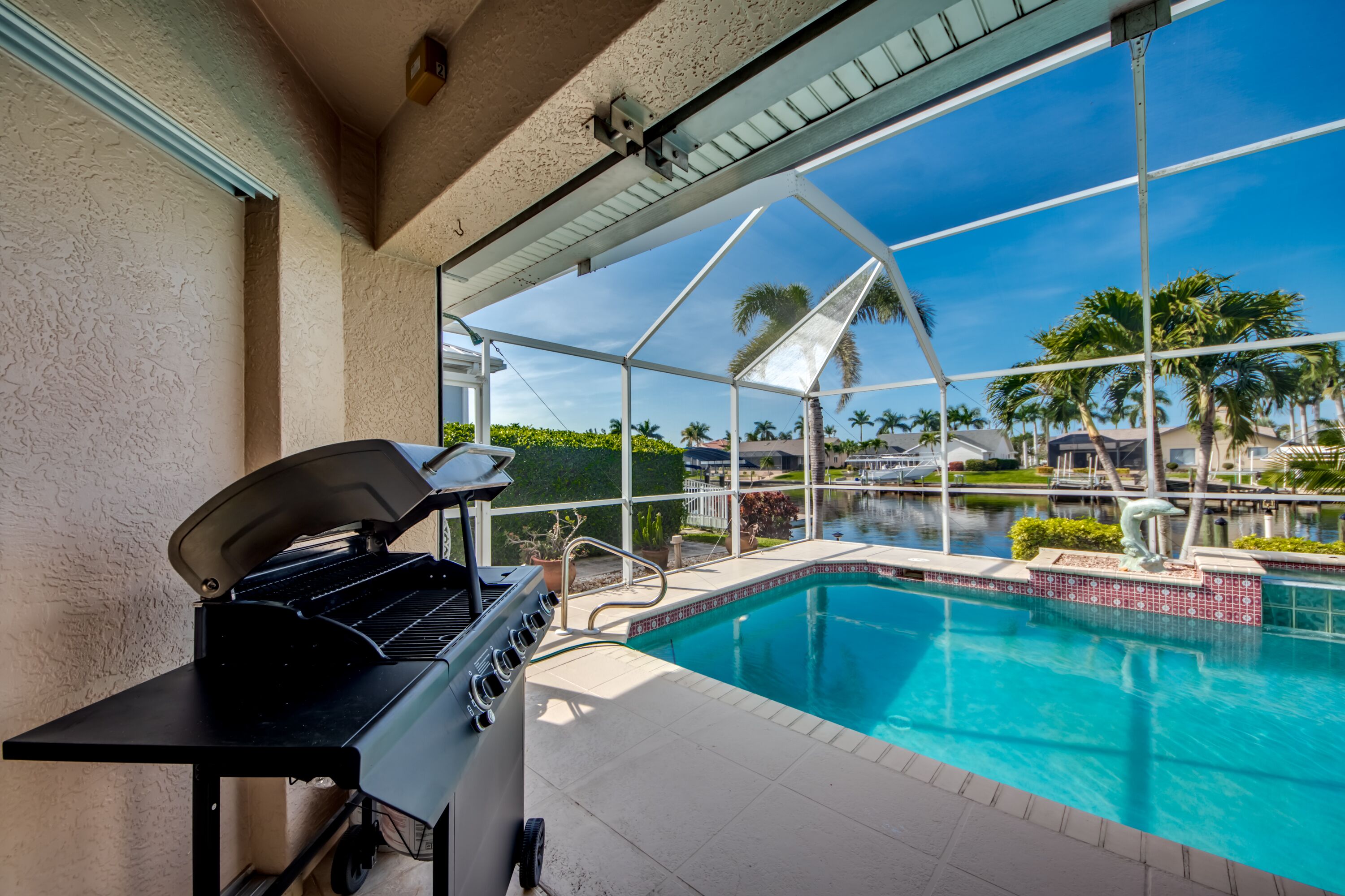 A poolside area with a grill and a view of a water body.