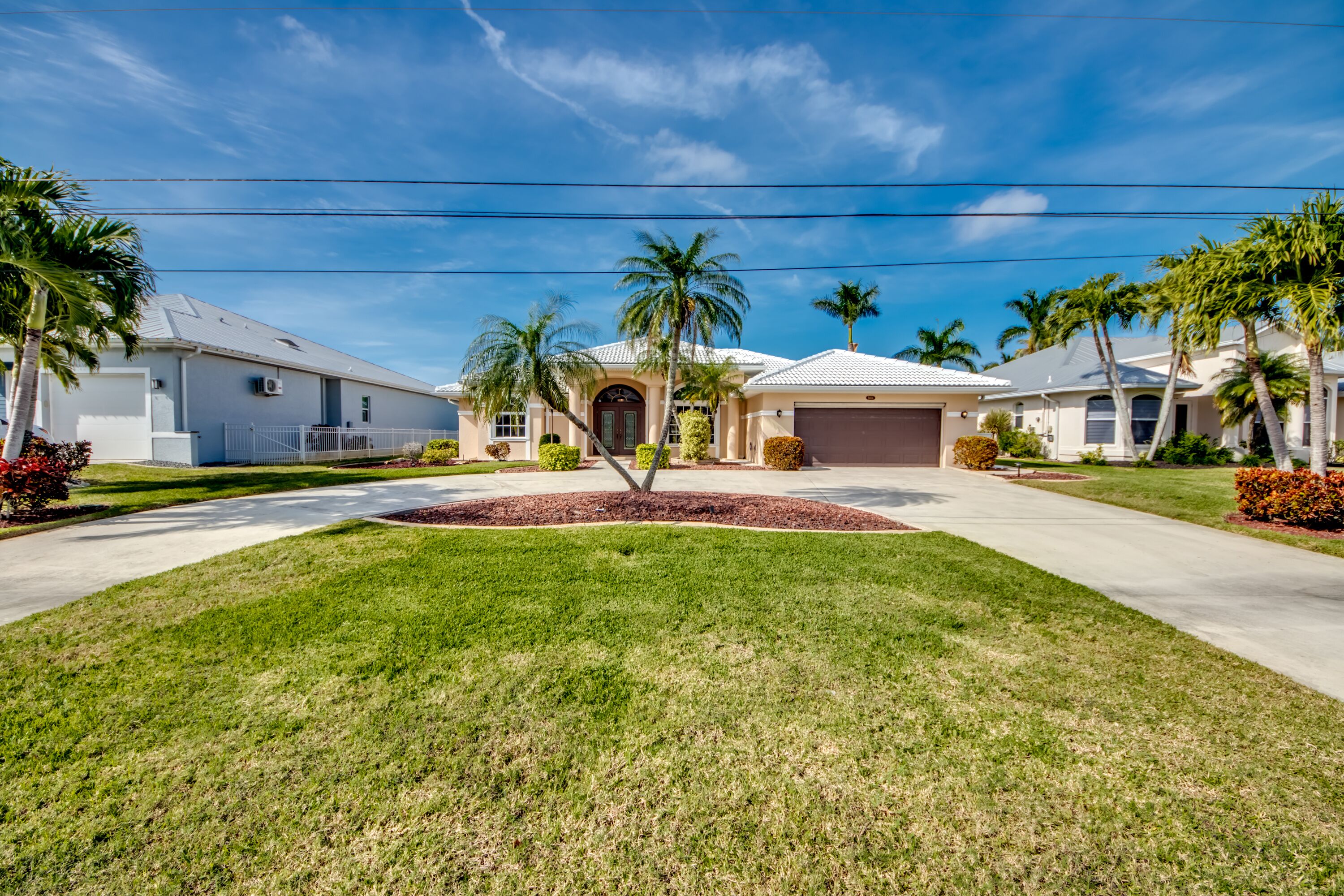 Un barrio residencial con casas, palmeras y un césped bien cuidado.