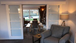 A living room with a grey sofa, a small coffee table, and a dining area with a table and chairs. - Tynemouth Your Home Away From Home - Pass the Keys (North Shields)