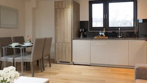 A modern kitchen with a window, a dining area with a table and chairs, and a built-in cabinet. - Capacity House · Central Tower Bridge Apartment (London)