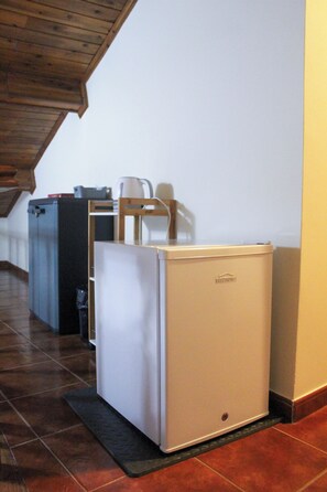 A compact kitchenette with a refrigerator, a coffee maker, and a microwave. - Vieira Rooms Natural Pools (Ponta Delgada)