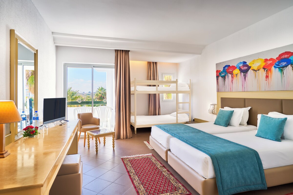 A hotel room with a bed, a desk, a chair, a television, and a window with curtains.