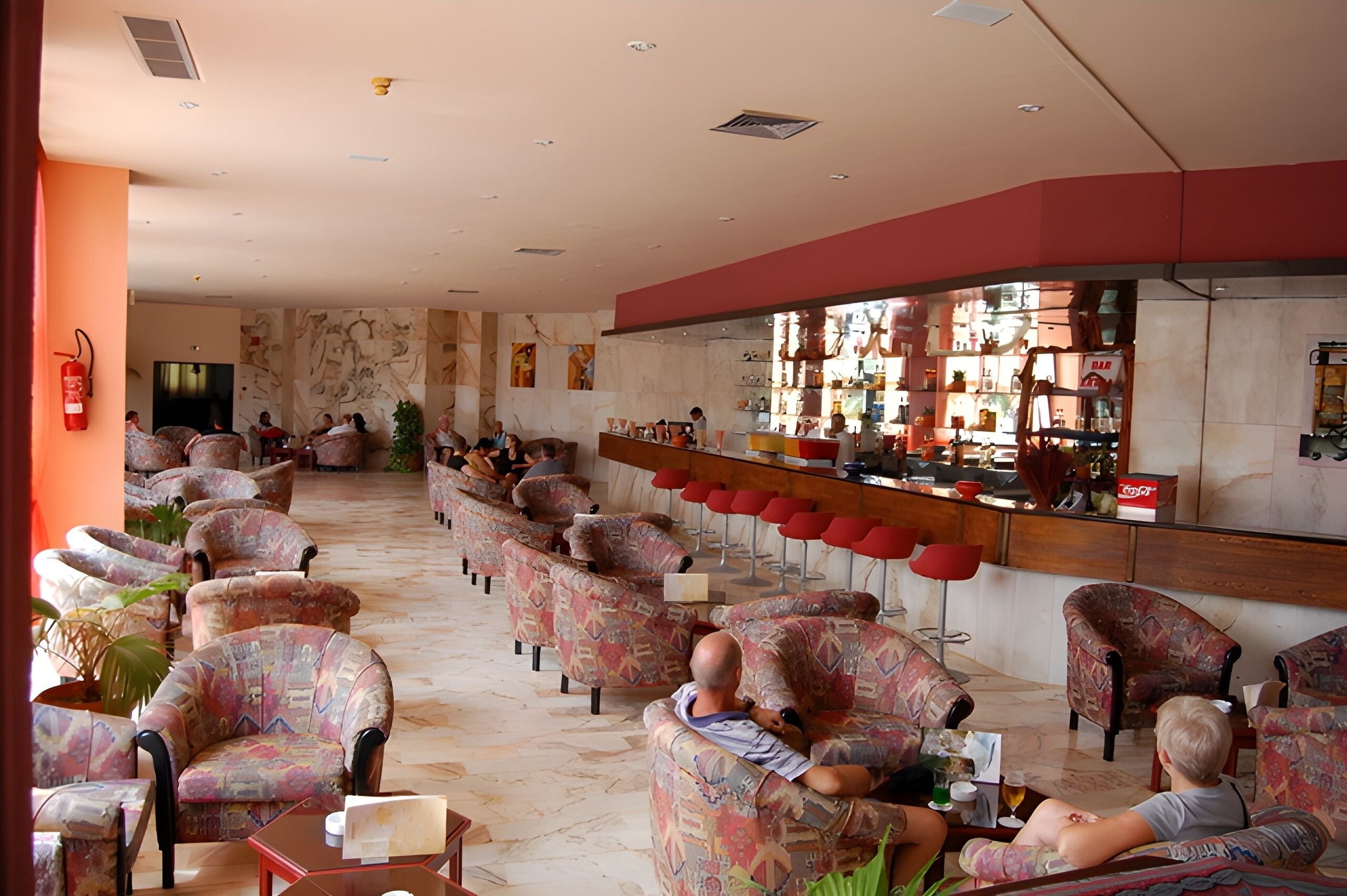 A spacious lobby with patterned chairs and a bar area.