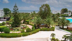A resort with a pool, palm trees, and a view of the ocean. - Monarque El Fatimi Mahdia (Mahdia)