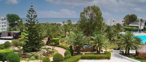 A resort with a pool, palm trees, and a view of the ocean.