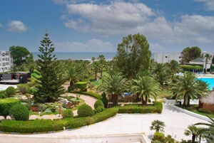 Un resort con piscina, palmeras y vista al océano.