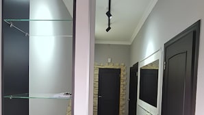 A hallway with a mirrored wall, a ceiling light, and a door with a TV.