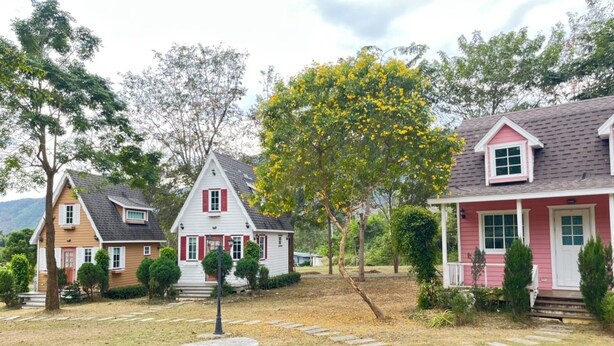 Un barrio residencial con tres casas, cada una de estilo arquitectónico y color diferente.