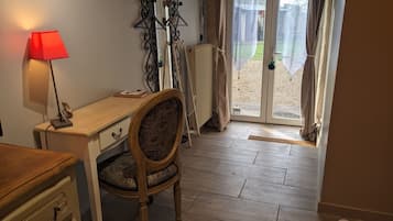 Une pièce avec un bureau en bois, une chaise dotée d’un coussin à motifs, une lampe rouge et un radiateur.