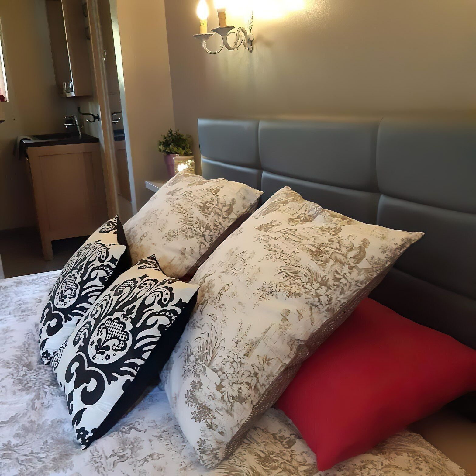 A bed with patterned pillows and a red accent pillow.