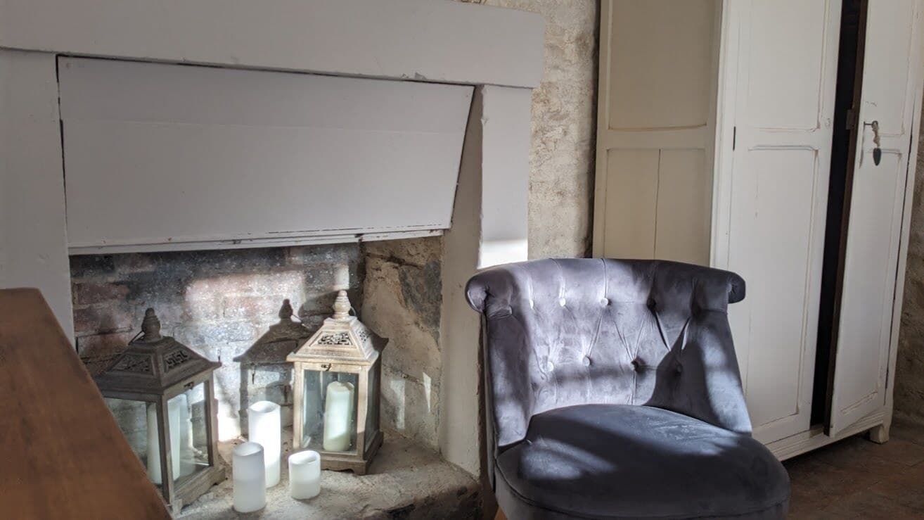A room with a fireplace, a chair, and two lanterns.