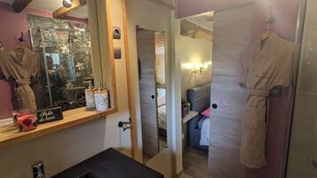 A bathroom with a mirror, a sink, a robe hanging, and a sign reading 'Salle de bain'.