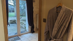 A room with a sliding glass door leading to an outdoor area, a radiator, and a robe hanging on a wooden hanger. - Domaine Les Feuillants  (Crouzilles)