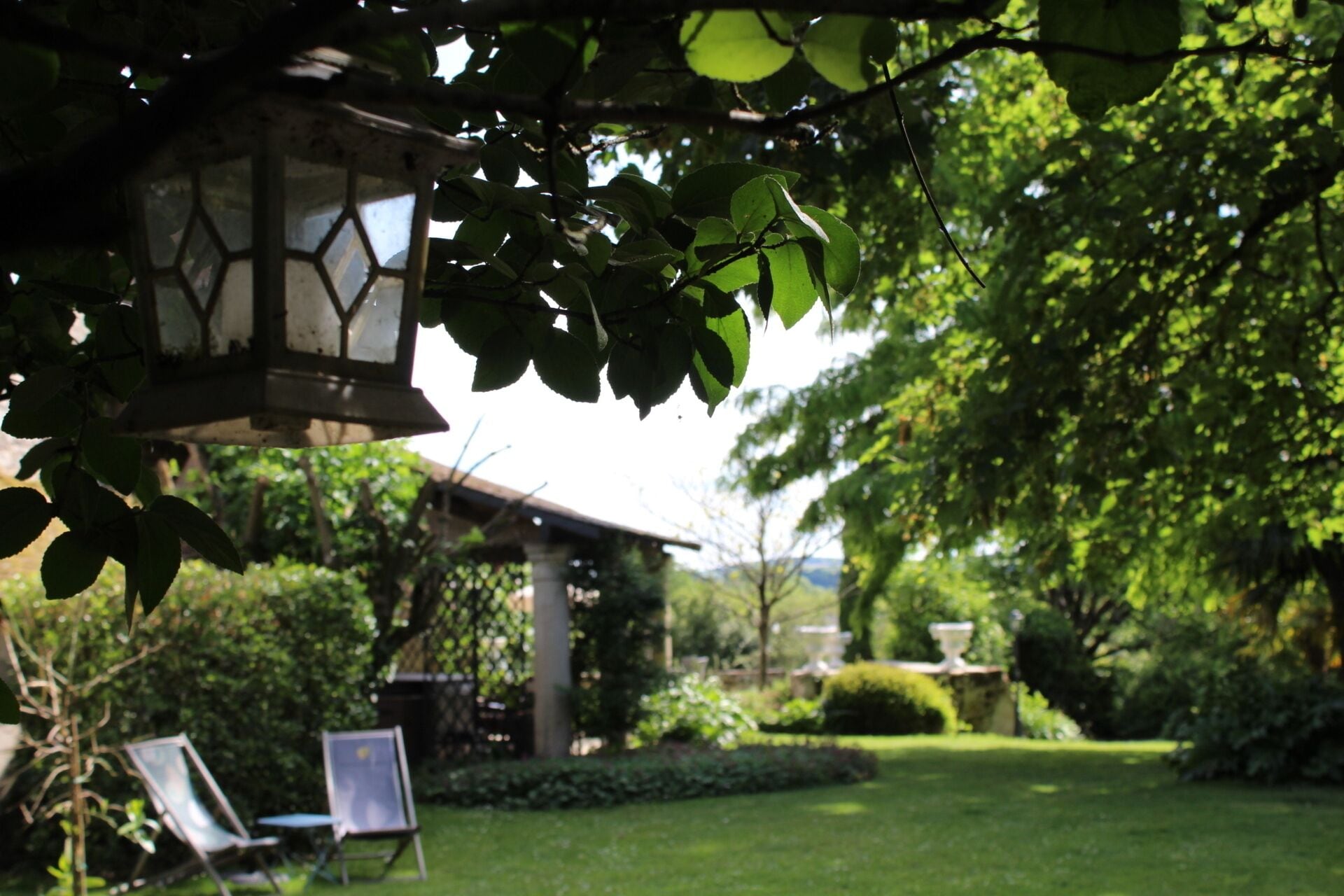 A garden with a gazebo, a lawn, and a hanging lantern.