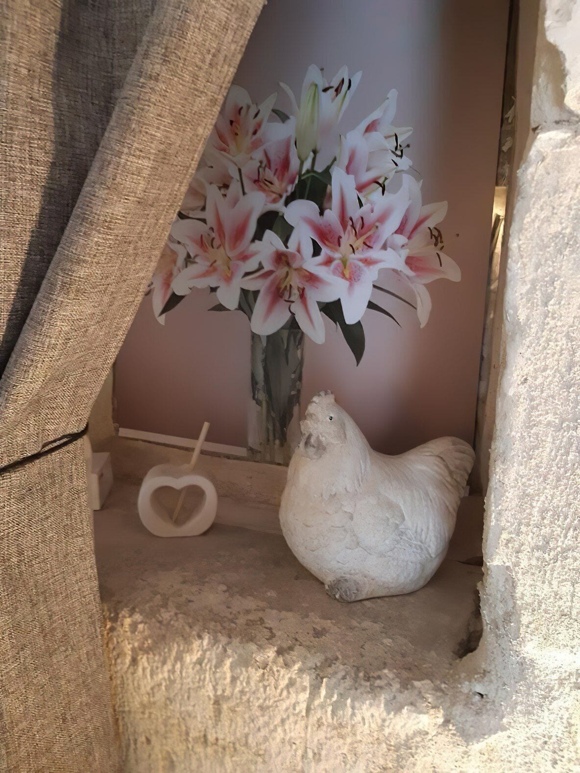 Et rustikt interiør med en hvid kyllingesulptur, en hjerteformet genstand og en vase med blomster.