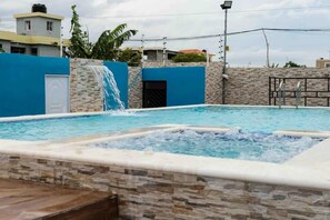 Relax by the pool surrounded by a serene water feature and lush surroundings.