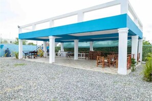 Relax under the shaded canopy, surrounded by comfortable seating and a staircase leading to an upper level.
