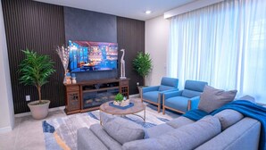 Ein modernes Wohnzimmer mit Flachbildfernseher, zwei Sofas, einem Couchtisch und zwei Blumentöpfen.