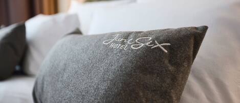 A pillow with the inscription "June Six Hotel" on a bed.