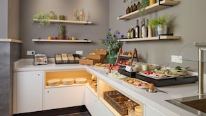 Een verzorgd buffetgedeelte met diverse soorten eten, een broodrooster en decoratieve planten op planken.