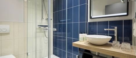 A modern bathroom with a glass-enclosed shower, a white sink, and a mirror above the sink.