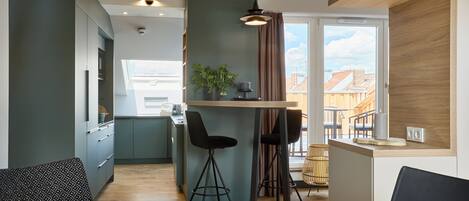 Una cocina moderna con comedor, que incluye una mesa de madera, taburetes de bar y vistas a la ciudad.