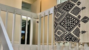 A staircase with white railings leading to a second floor, a kitchen area with a stove and sink, and a patterned wall hanging. - Modern 2BD Condo Near TOWN! Fire Pit + Pool Table (Pigeon Forge)