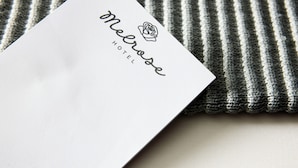Tarjeta de presentación de hotel en blanco con el nombre 'Melrose Hotel' y un logotipo.
