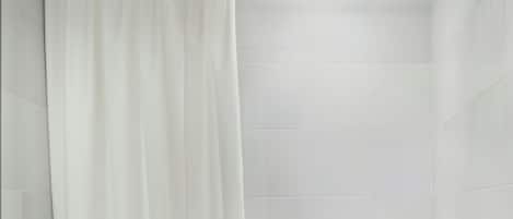 A modern bathroom with a toilet, bathtub, and shower curtain.