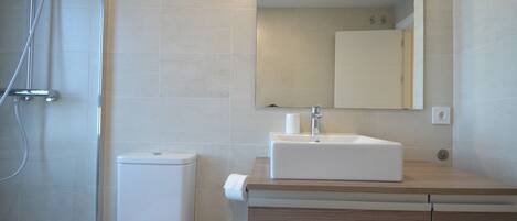 A modern bathroom with a shower, toilet, sink, and mirror.