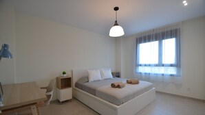 Une chambre à coucher moderne avec un lit, des tables de chevet, un bureau et une fenêtre avec des rideaux.