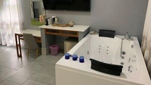 A modern bathroom with a large bathtub, a vanity with a mirror, and a television mounted on the wall. - Ecolux Boutique Hotel Mozambique (Marracuene)