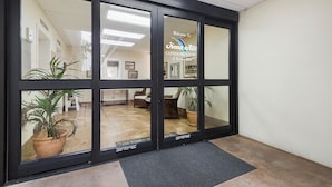 A glass door entrance to a building with a sign reading "Welcome to Kona Ai Condominiums E. Kona Mai."