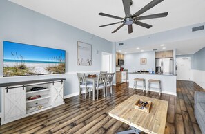 A modern kitchen with a central island, a dining area with a view of the beach, and a ceiling fan.
