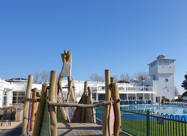 A playground with climbing structures and a pool area.